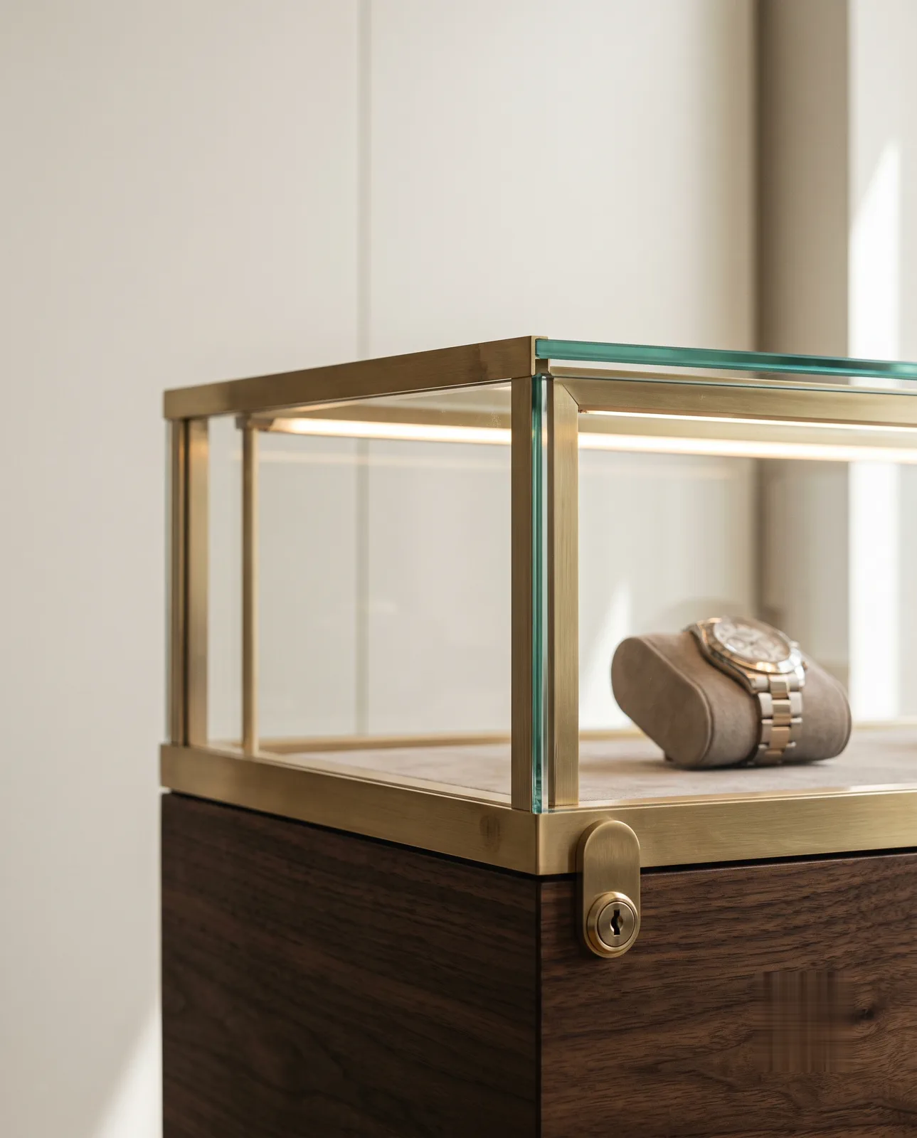 Vitrina de joyería en latón y vidrio con reloj sobre soporte de ante
